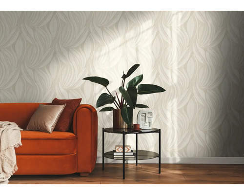 Helles Wohnzimmer mit Tapete in beige-weißem Blättermuster, einem orangefarbenen Sofa mit Kissen und einem Beistelltisch mit Zimmerpflanze.
