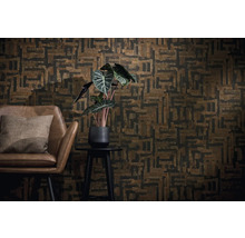 Wandgestaltung mit geometrisch gemusterter Tapete in Braun und Schwarz, brauner Ledersessel mit Kissen und eine Zimmerpflanze auf einem Beistelltisch.