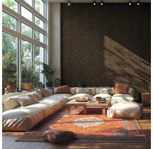 Modernes helles Wohnzimmer mit dunkler Mustertapete großem weißen Ecksofa buntem Orientteppich Holztisch und bodentiefen Fenstern.