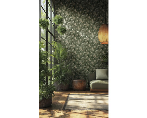 Vliestapete mit tropischem Blattmuster in Grün und Creme in einem hellen Raum mit Zimmerpflanzen, grünem Sofa und geflochtener Hängelampe.