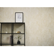 Vliestapete in beige Betonoptik an einer Wand hinter einem schwarzen Metallregal mit dekorativen Objekten.