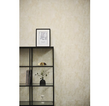 Vliestapete mit strukturierter Optik an einer Wand hinter einem schwarzen Metallregal in einem hellen, modern eingerichteten Raum.
