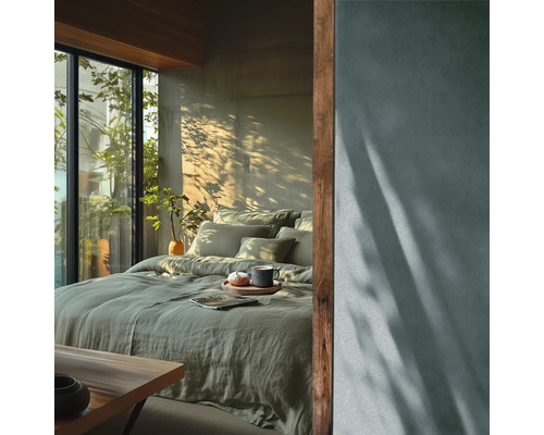 Modernes Schlafzimmer mit grüner Leinenbettwäsche, großem Fenster mit Blick ins Grüne und natürlichem Licht mit Pflanzenschatten an der Wand.