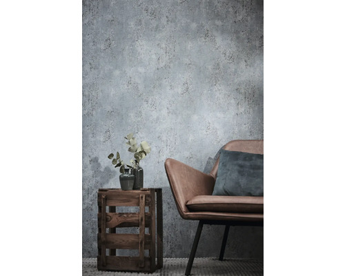 Vliestapete in Betonoptik im Wohnzimmer mit Sessel aus Lederimitat und Holzkiste als Beistelltisch.