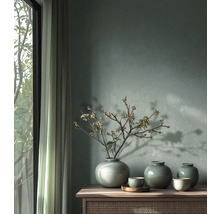 Wandgestaltung mit grüner Wandfarbe, drei Keramikvasen mit Krakelee-Glasur und Zweigen auf einem Sideboard aus Holz neben einem hellen Fenster.