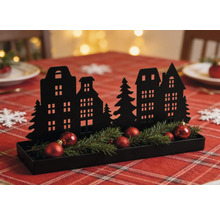 Schwarze Weihnachtsdekoration aus Metall mit Häusersilhouette, Tannengrün und roten Kugeln in einem Tablett auf einem festlich gedeckten Tisch.