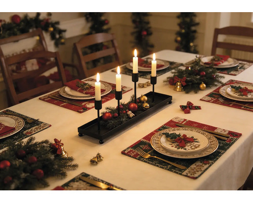Schwarzer länglicher Kerzenhalter aus Metall mit vier weißen Kerzen auf einem festlich gedeckten Weihnachtstisch mit Tannenzweigen.
