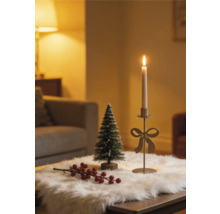 Weihnachtliche Tischdekoration mit Kerzenhalter mit Schleife, kleiner Tanne und roten Beeren auf weißem Kunstfell.
