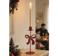 Roter Kerzenständer aus Metall mit Schleifen-Design und brennender Stabkerze in weihnachtlicher Umgebung.