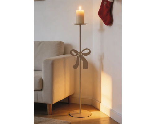 Bodenkerzenständer mit dekorativer Schleife, hoher Stab und Stumpenkerze, im Wohnzimmer neben einem Sofa platziert.