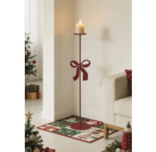 Hoher Bodenkerzenständer aus Metall mit Schleife und brennender Stumpenkerze in einem weihnachtlich dekorierten Wohnzimmer.