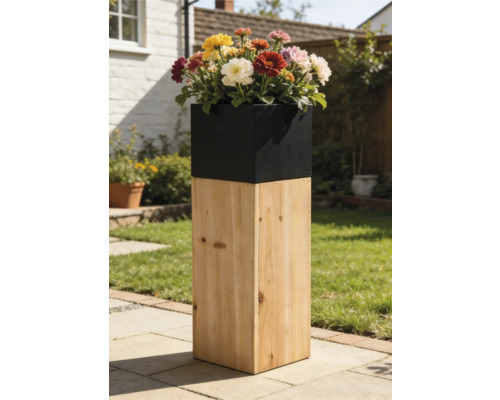 Hoher Säulen-Pflanzkübel mit Sockel aus Naturholz und schwarzem Einsatz mit bunten Blumen auf einer Gartenterrasse.
