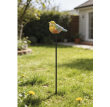 Gartenstecker mit einer kleinen Vogelfigur auf einem langen Metallstab, platziert in einer Rasenfläche vor einem Gartenhintergrund.