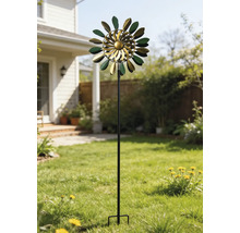 Kinetisches Windspiel aus Metall in Grün und Gold mit blattförmigen Elementen auf einem hohen Stab in einem sonnigen Garten auf dem Rasen.
