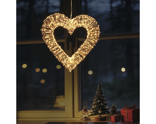 Beleuchtetes Deko-Herz aus Metalldraht mit zahlreichen warmweißen LED-Lämpchen, hängend vor einem Fenster mit Weihnachtsdekoration.