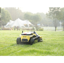 Gelber Mähroboter mit Kettenantrieb bei der Arbeit auf einer weitläufigen grünen Rasenfläche.