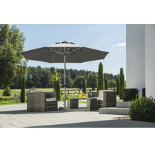 Moderner grauer Gartenschirm auf einer gepflasterten Terrasse mit Polyrattan Sessel und Beistelltisch in hellem Garten.