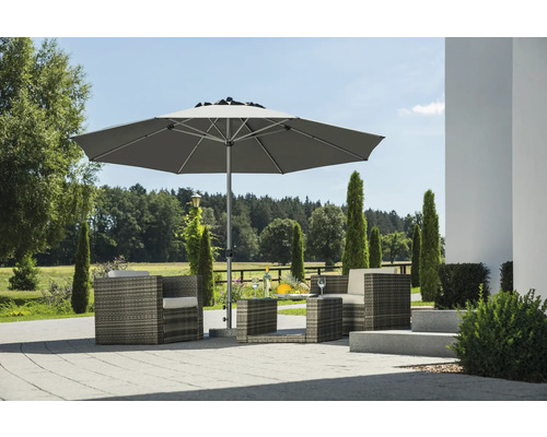 Moderner grauer Gartenschirm auf einer gepflasterten Terrasse mit Polyrattan Sessel und Beistelltisch in hellem Garten.