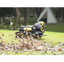 Roboter Laubbläser auf Ketten bläst trockenes Laub auf einer Rasenfläche im Garten weg.
