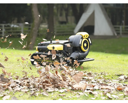 Roboter Laubbläser auf Ketten bläst trockenes Laub auf einer Rasenfläche im Garten weg.