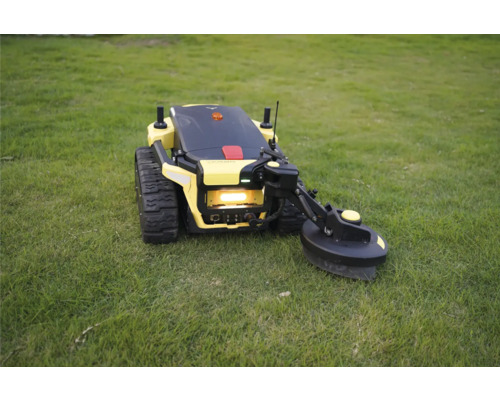 Gelber Mähroboter mit Raupenantrieb und seitlichem Trimmerarm auf einer Rasenfläche.