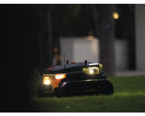 Autonomer Yarbo Gartenroboter auf einer Rasenfläche bei Nacht mit eingeschalteten Scheinwerfern.