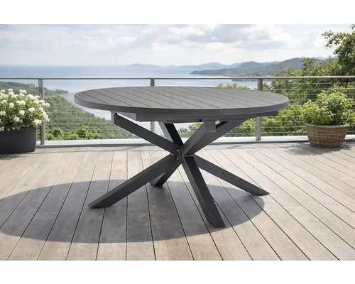 Moderner runder Gartentisch aus Metall mit sternförmigem Gestell auf einer hellen Terrasse mit Meerblick.
