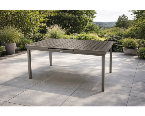Rechteckiger Gartentisch mit Aluminiumgestell und Tischplatte in Holzoptik auf einer Terrasse.