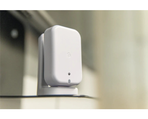 Kleiner weißer rechteckiger Smart-Home-Sensor mit abgerundeten Ecken auf einer passenden Halterung.
