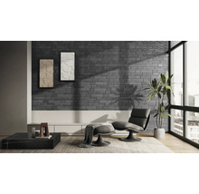 Modernes Wohnzimmer mit Wandverblendern in dunkelgrauer Backsteinoptik, einem Sessel mit Hocker, großem Fenster und einer Zimmerpflanze.