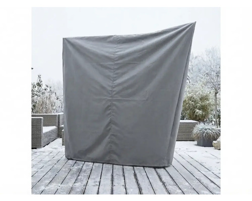 Graue Schutzhülle für einen Strandkorb auf einer verschneiten Holzterrasse im Garten.