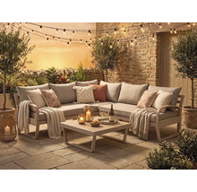 Ecklounge-Set aus Holz mit grauen Polstern, Couchtisch, Kissen, Decken, Lichterkette und Laternen auf einer Steinterrasse vor Steinmauer.