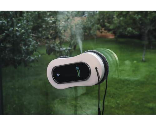 Lifenaxx Fensterreinigungsroboter mit Sprühfunktion reinigt eine Fensterscheibe vor einem Gartenhintergrund.