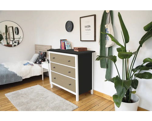 Moderne Kommode mit drei Schubladen in Wiener Geflecht Optik, weißem Rahmen und schwarzer Oberplatte in einem hellen Schlafzimmer.