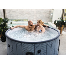 Paar entspannt in rundem, gemustertem aufblasbarem Whirlpool auf einer modernen Terrasse mit Pflanzen.