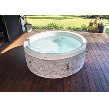 Runder Whirlpool mit grau gemusterter Außenwand auf einer Holzterrasse im Garten.