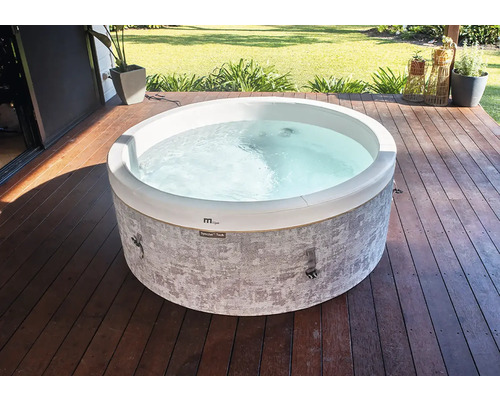 Runder Whirlpool mit grau gemusterter Außenwand auf einer Holzterrasse im Garten.