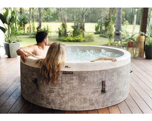MSpa aufblasbarer Whirlpool mit zwei Personen auf einer Holzterrasse in einem hellen Garten.