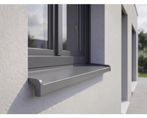 Außenfensterbank aus Aluminium montiert an einer verputzten Fassade unter einem Fenster.