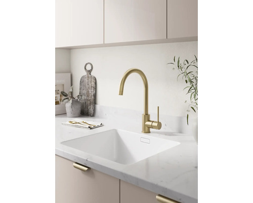 Moderne helle Küche mit einer Hochbogen-Küchenarmatur, einem Unterbaubecken und einer Arbeitsplatte in Steinoptik.