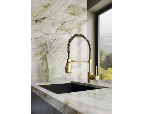 Moderne Küchenarmatur mit Spiralfeder und Ausziehbrause, Einhandmischer in Gold-Optik, montiert auf einer hellen Marmor-Arbeitsplatte.