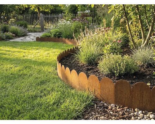 Gewellte Rasenkante aus Metall in Rost-Optik trennt ein bepflanztes Beet von einer Rasenfläche in einem hellen Garten.