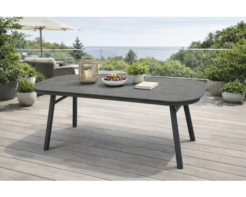 Moderner, rechteckiger Gartentisch mit abgerundeten Ecken auf einer hellen, geräumigen Terrasse. Dunkelgrauer Tisch mit Metallgestell.
