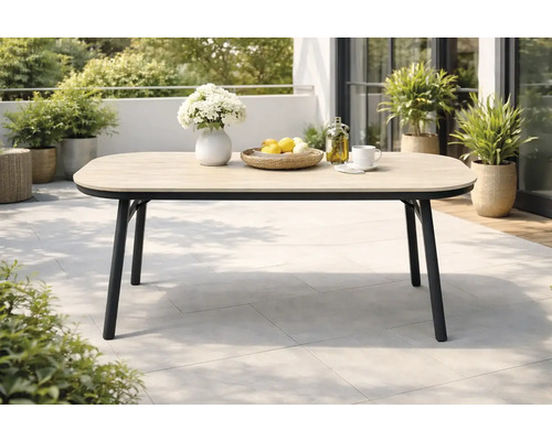 Moderner Gartentisch auf einer Terrasse mit Tischplatte in Holzoptik und schwarzem Metallgestell, umgeben von Pflanzen.