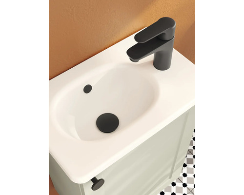 Waschbecken mit mattschwarzer Armatur und Ablauf auf einem hellen Waschtischunterschrank in einem modern gestalteten Badezimmer.