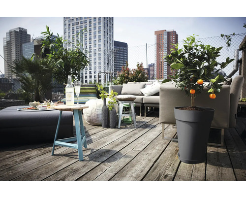 Helle Dachterrasse mit Holzdeck, modernen grauen Lounge-Möbeln, einem Kunststoff-Pflanzkübel mit Zitrusbaum und Blick auf die Skyline der Stadt.