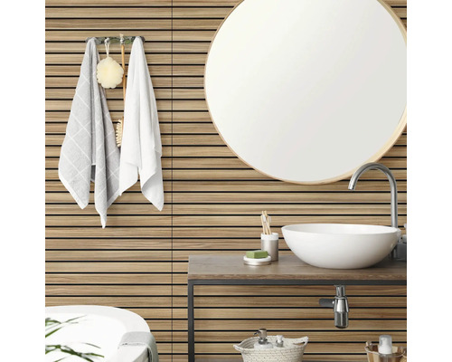 Badezimmer mit horizontalen Wandpaneelen in Holzoptik, einem runden Spiegel, einem weißen Aufsatzwaschbecken und Handtüchern an der Wand.