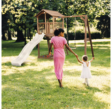 Spielturm aus Holz mit Rutsche, Schaukel, Spielhaus und Sandkasten in einem hellen Garten mit einer Frau und einem Kind.