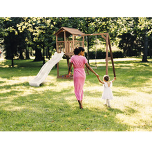 Hölzerner Spielturm mit Rutsche und Schaukel in einem hellen Garten mit Frau und Kind.