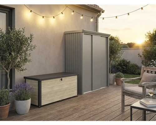 Außenbereich mit moderner Aufbewahrungsbox in Holzoptik und grauem Metall-Gartenschrank auf einer Holzterrasse mit Lichterkette und Sitzbereich.